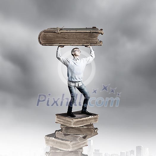 Young man holding huge book above head Young man holding huge book above head