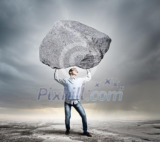 Young strong man holding huge stone above head