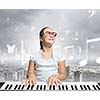 Young girl sitiing at digital piano with red glasses