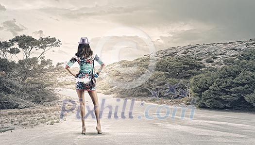 Rear view of young woman standing aside of road