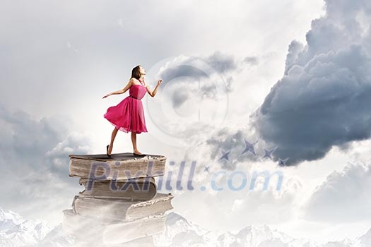 Woman in red dress standing on pile of books Woman in red dress standing on pile of books
