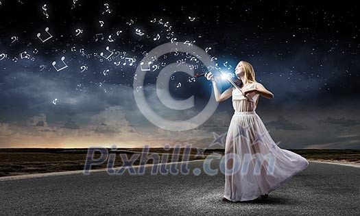 Young woman in white dress playing violin at night