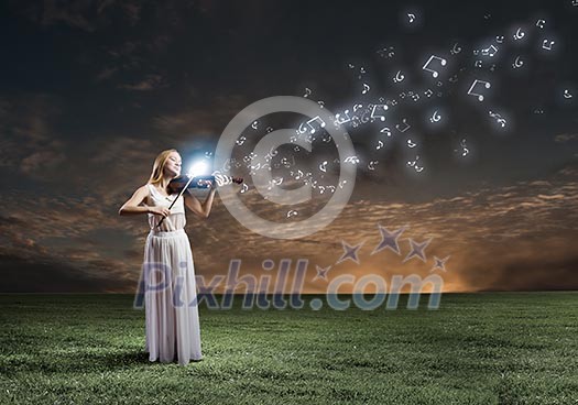 Young woman in white dress playing violin at night