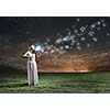 Young woman in white dress playing violin at night