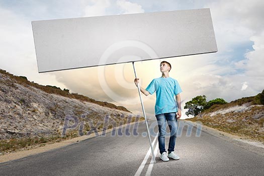Young man on road holding blank banner. Place for text