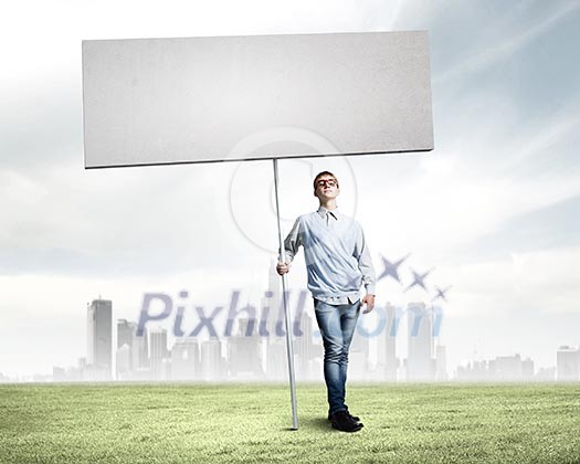 Young man against city background holding blank banner. Place for text