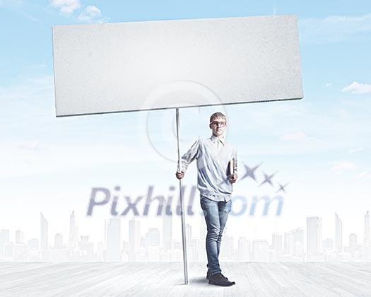 Young man against city background holding blank banner. Place for text Young man against city background holding blank banner. Place for text