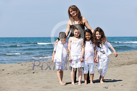 group portrait of happy childrens with young female  teacher on beach