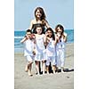 group portrait of happy childrens with young female  teacher on beach