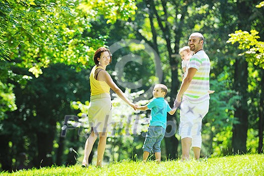 happy young couple with their children have fun at beautiful park outdoor in nature