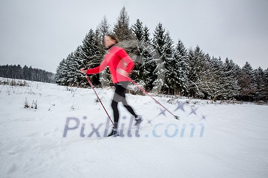 Cross-country skiing: young woman cross-country skiing on a  winter day (motion blurred image)