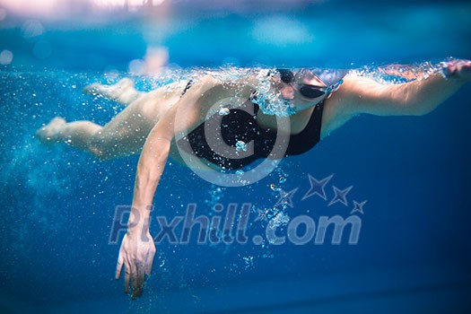 Female swimmer in an indoor swimming pool - doing crawl (shallow DOF) Female swimmer in an indoor swimming pool - doing crawl (shallow DOF)