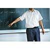 teacher teaching mathematics while pointing at blackboard in classroom