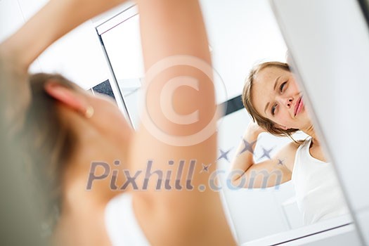 Morning stretch - Pretty, young woman in front of the mirror in the bathroom on an early morning