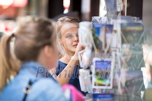 Pretty, young woman buying a postcard on a street (shallow DOF) Pretty, young woman buying a postcard on a street (shallow DOF)