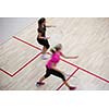 Two female squash players in fast action on a squash court (motion blurred image; color toned image)