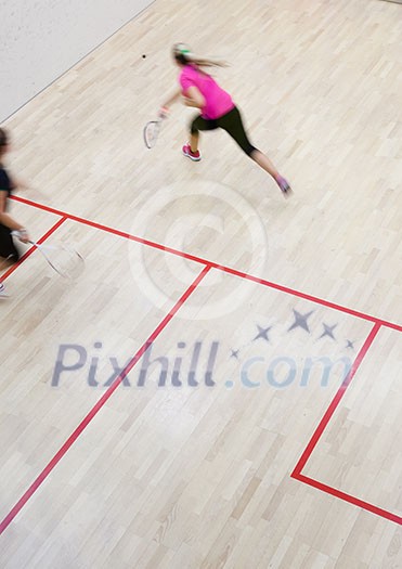Two female squash players in fast action on a squash court (motion blurred image; color toned image) Two female squash players in fast action on a squash court (motion blurred image; color toned image)