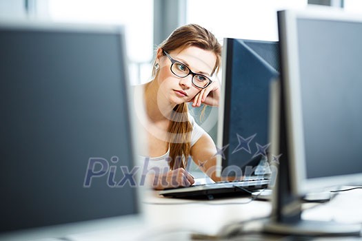 Pretty, female student looking at a desktop computer screen, learning unpleasant news about her exam results. University/office/school concept Pretty, female student looking at a desktop computer screen, learning unpleasant news about her exam results. University/office/school concept