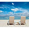 Two sun beach chairs on shore near ocean