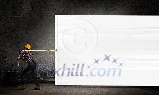 Image of woman engineer pulling blank white banner Image of woman engineer pulling blank white banner