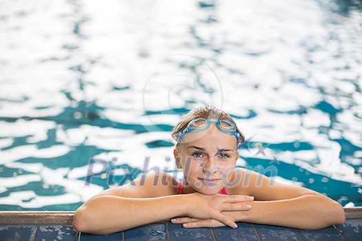 Female swimmer in an indoor swimming pool - looking at the camera, looking content after a good swim (shallow DOF)