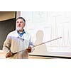 Senior chemistry professor giving a lecture in front of classroom full of students (shallow DOF; color toned image)