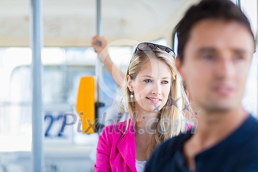 Pretty, young woman on a streetcar/tramway, during her commute to work (color toned image; shallow DOF)