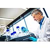 Senior male researcher carrying out scientific research in a lab (shallow DOF; color toned image)