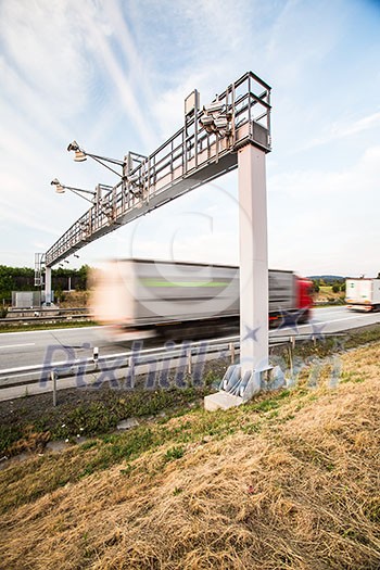 truck passing through a toll gate on a highway (motion blurred image; color toned image) truck passing through a toll gate on a highway (motion blurred image; color toned image)