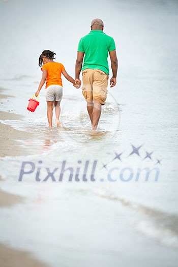 Father and daughter on the beach, walking hand in hand, father in thoughts, little girl beachcombing