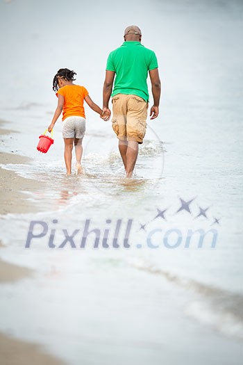 Father and daughter on the beach, walking hand in hand, father in thoughts, little girl beachcombing Father and daughter on the beach, walking hand in hand, father in thoughts, little girl beachcombing