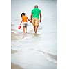 Father and daughter on the beach, walking hand in hand, father in thoughts, little girl beachcombing
