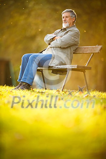 Senior man sitting on a bench in a park, enjoying retirement Senior man sitting on a bench in a park, enjoying retirement