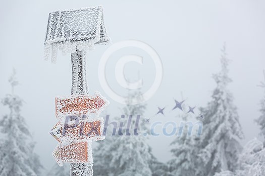 Extreme winter weather - hiking path sign covered with snow brought by strong wind during snowstorm