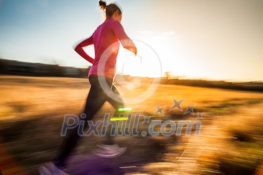 Young woman running outdoors on a lovely sunny winter/fall day (motion blurred image)