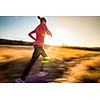 Young woman running outdoors on a lovely sunny winter/fall day (motion blurred image)