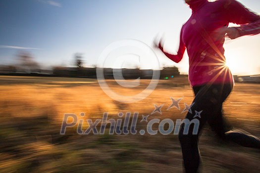 Young woman running outdoors on a lovely sunny winter/fall day (motion blurred image)