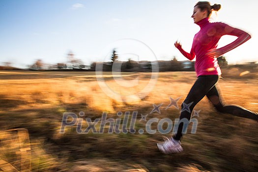 Young woman running outdoors on a lovely sunny winter/fall day (motion blurred image)