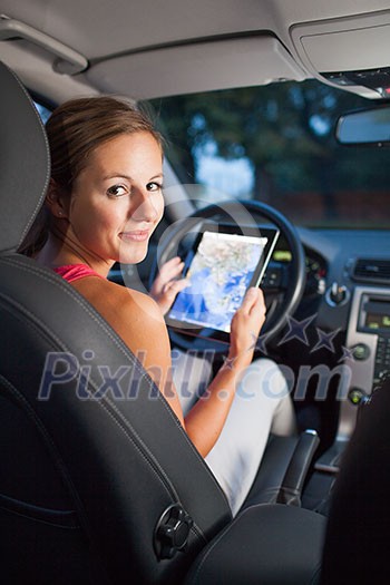 Pretty, female driver using her tablet computer (shallow DOF; color toned image)