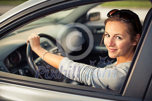 Pretty young woman driving her new car  (color toned image; shallow DOF)
