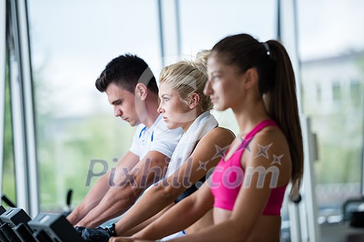 Beautiful group of young women friends  exercising on a treadmill at the bright modern gym