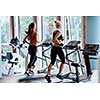 Beautiful group of young women friends  exercising on a treadmill at the bright modern gym