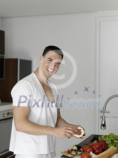 Handsome man cooking at home preparing salad in kitchen.