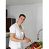 Handsome man cooking at home preparing salad in kitchen.