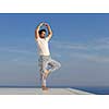 handsome young man practicing yoga on in modern home terace with ocean and sunset in background