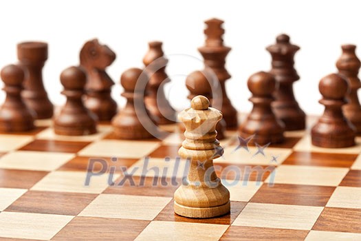 One king agains all - wooden chess pieces on chessboard. Selective focus, shallow depth of field