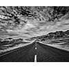 Travel forward concept background - road in Himalayas with mountains and dramatic clouds. Ladakh, Jammu and Kashmir, India. Black and white version