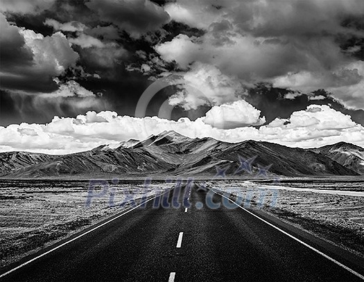 Travel forward concept background - road on plains in Himalayas with mountains and dramatic clouds. Manali-Leh road, Ladakh, Jammu and Kashmir, India. Black and white version