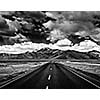 Travel forward concept background - road on plains in Himalayas with mountains and dramatic clouds. Manali-Leh road, Ladakh, Jammu and Kashmir, India. Black and white version