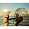 Myanmar travel attraction landmark - two traditional Burmese fishermen at Inle lake, Myanmar famous for their distinctive one legged rowing style on sunrise sunset
